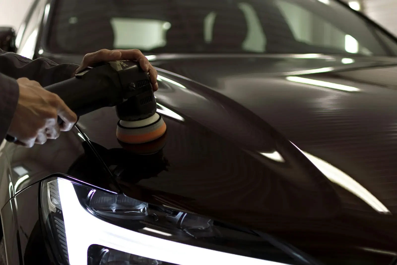 Hand poliert die Motorhaube eines dunklen Autos