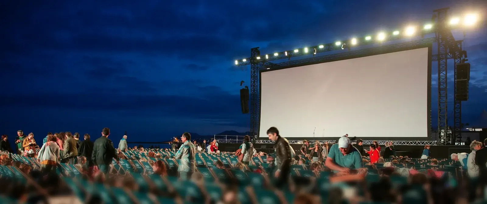 Open-Air-Kino mit grosser Leinwand und Publikum in der Dämmerung