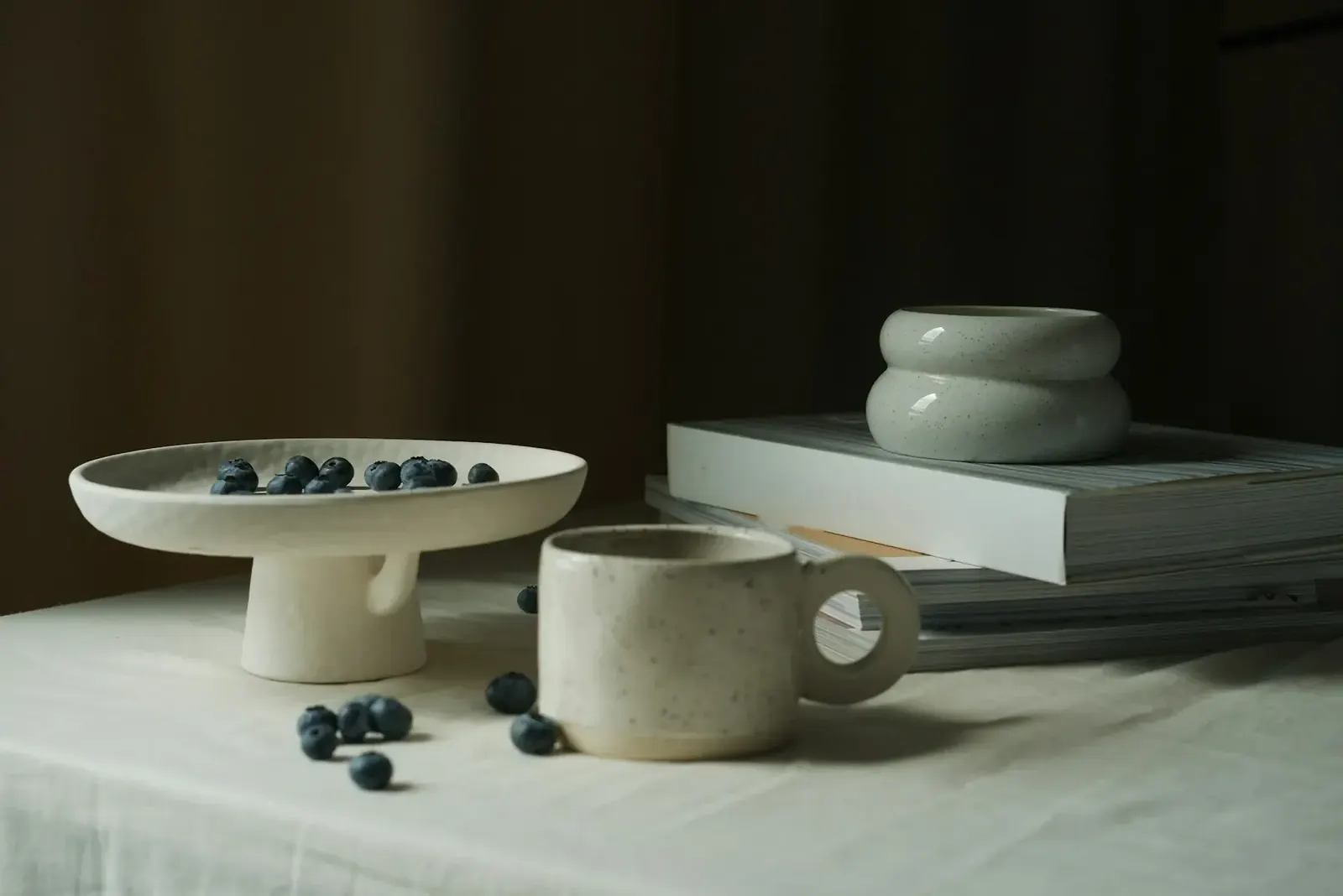 Keramikschalen, Tasse und Bücher auf einem hellen Tisch